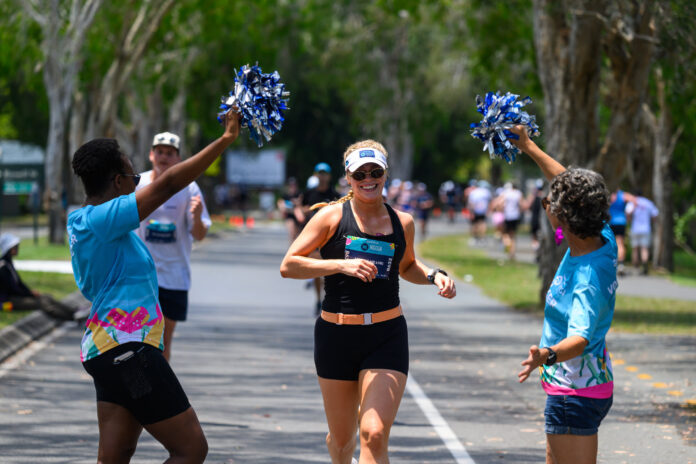 A triathlon festival participant runs along a road and is cheered by spectators.