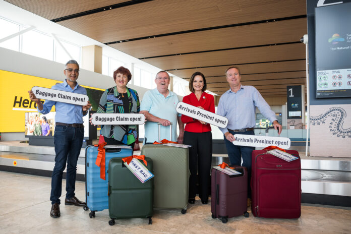 Four people with their luggage in the Sunshine Coast Airport terminal.